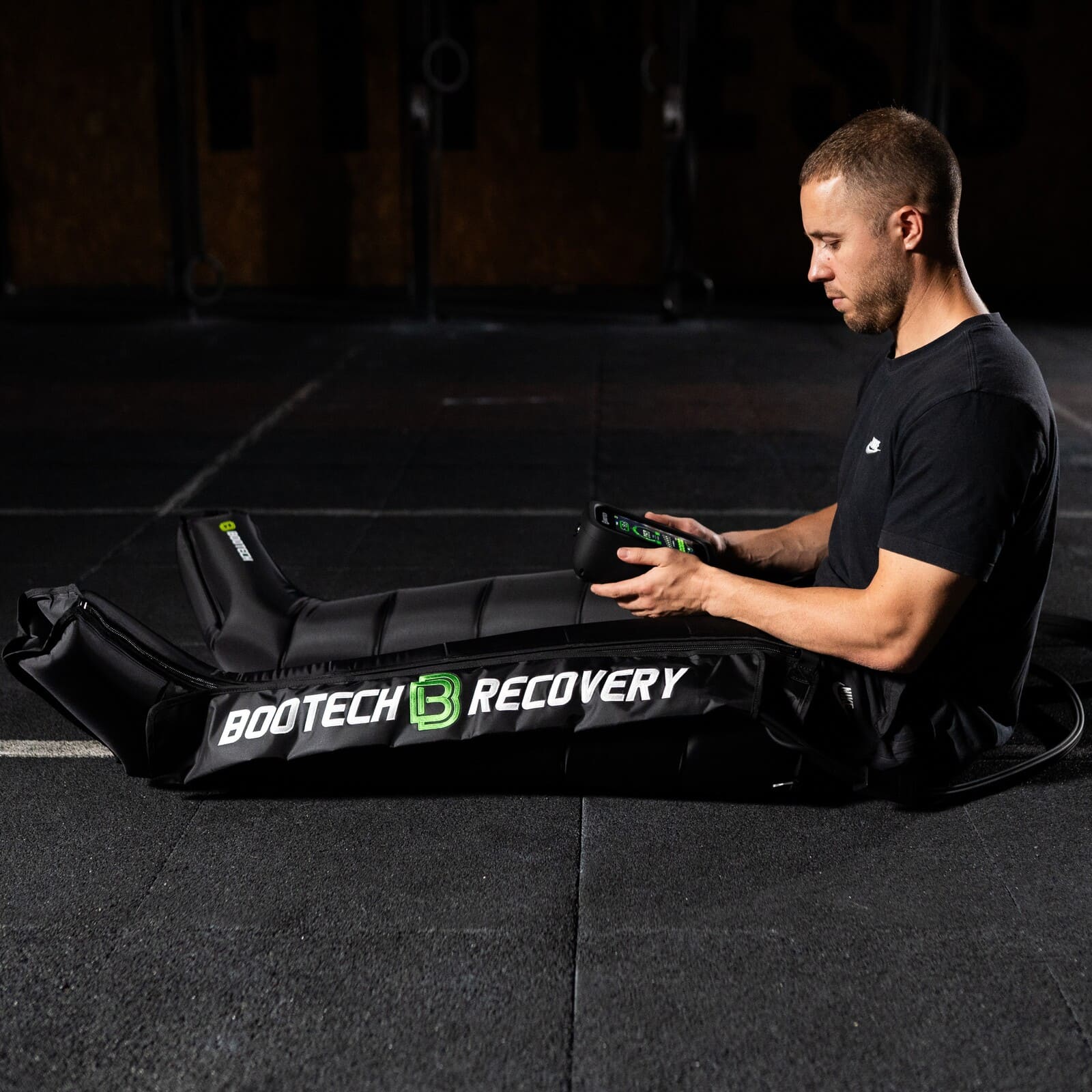 Hombre usando botas de presoterapia Bootech Recovery en gimnasio para recuperación deportiva