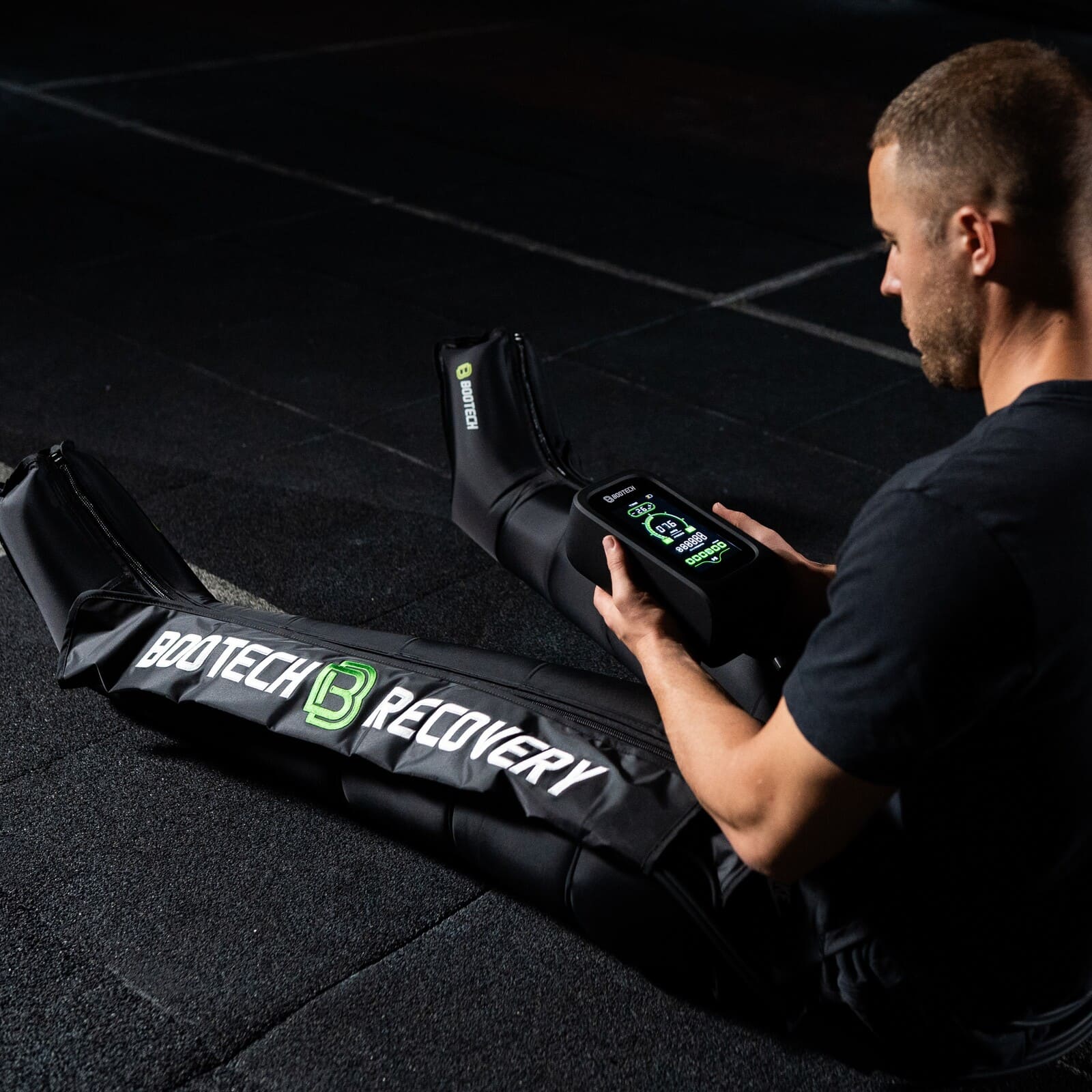 Hombre usando botas de presoterapia Bootech Recovery para recuperación deportiva en casa