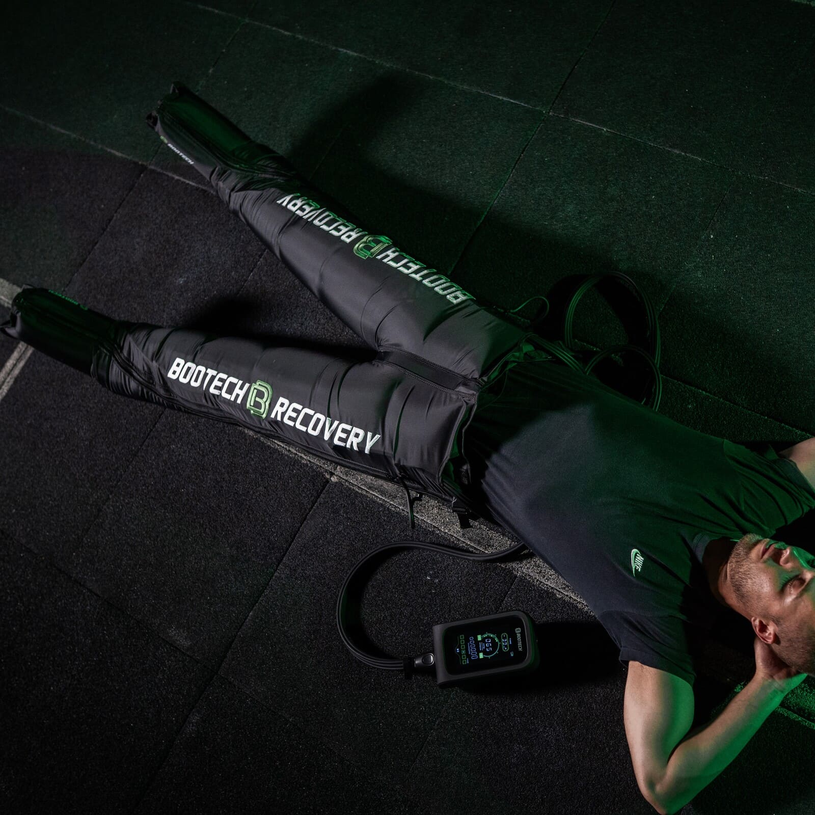 Hombre usando pantalones de presoterapia Bootech Recovery en gimnasio para recuperación deportiva
