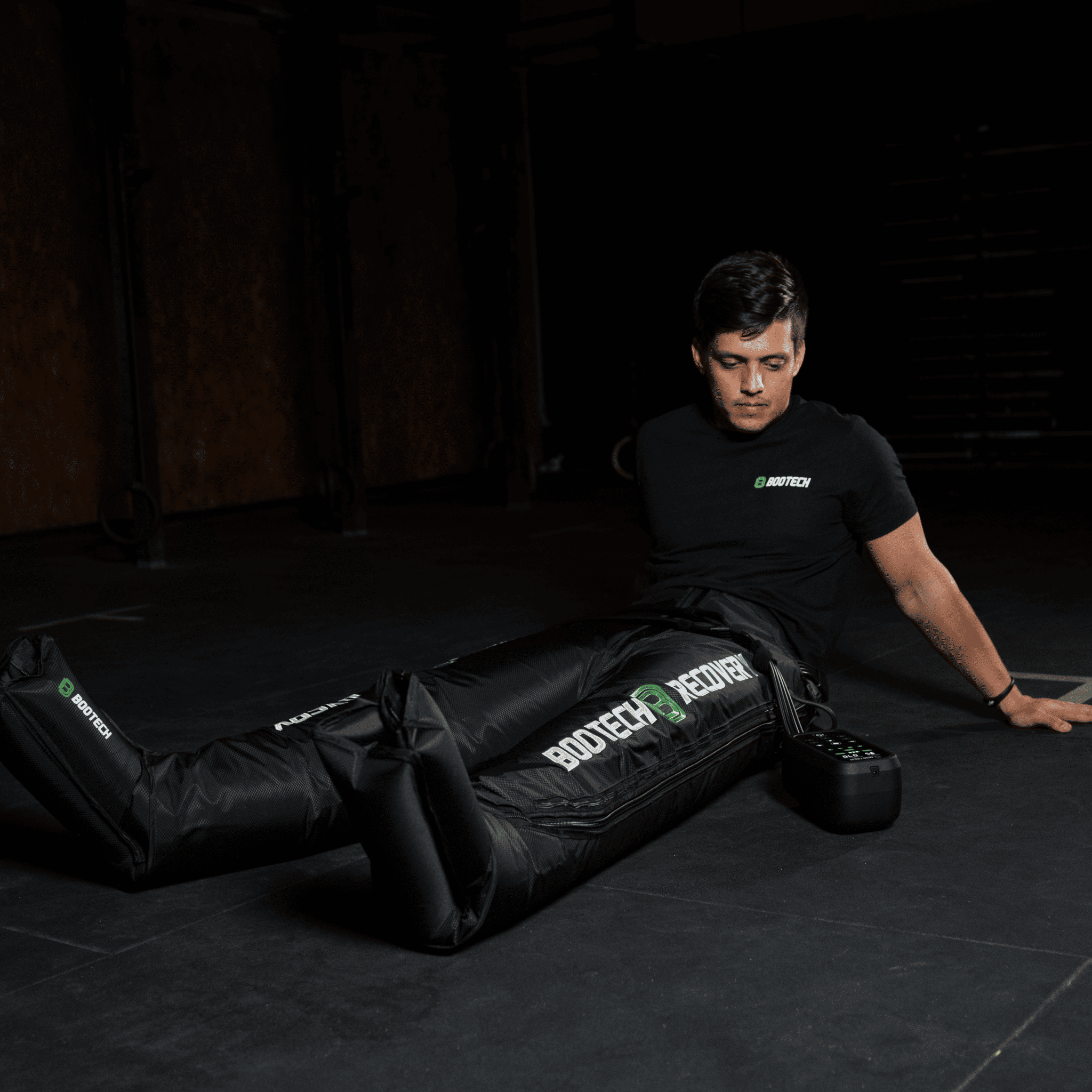 Hombre usando presoterapia BOOTECH para recuperación deportiva en ambiente de gimnasio.