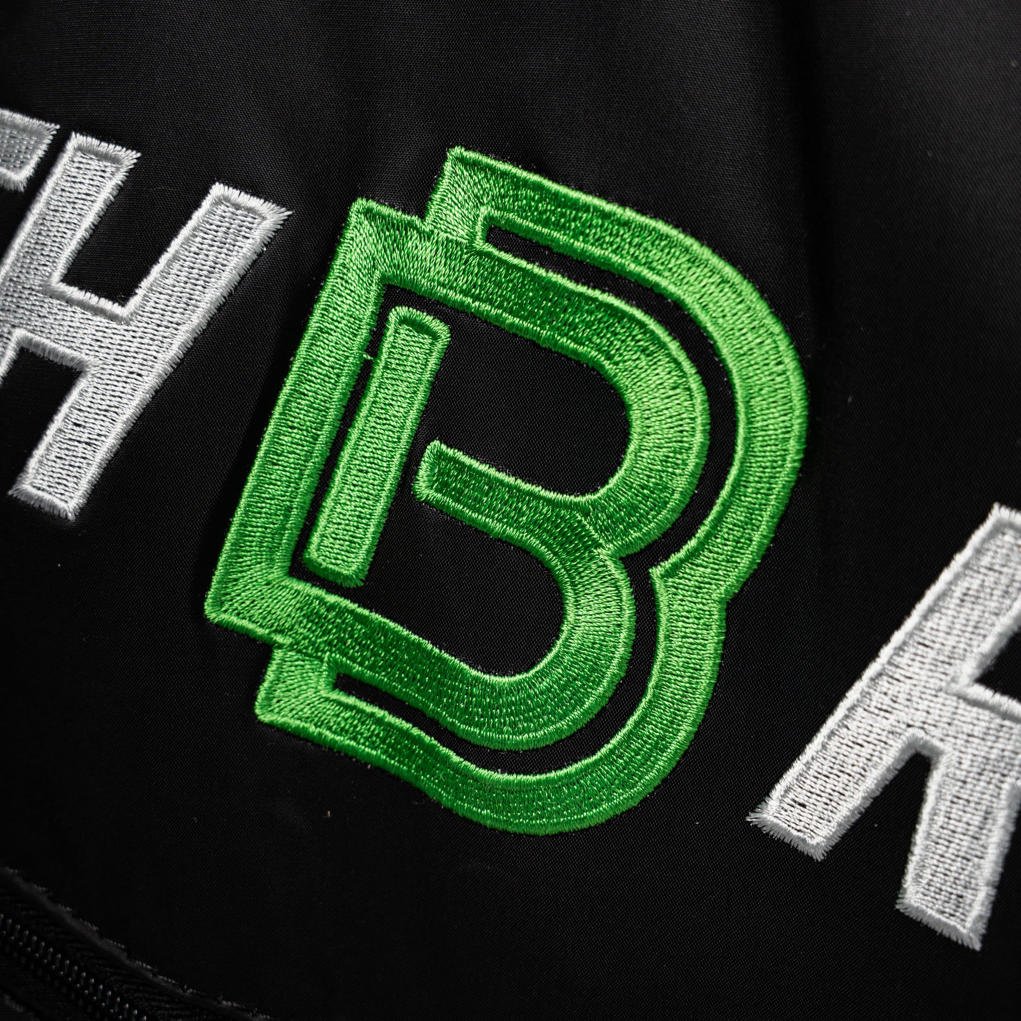 Bordado del logo verde de Bootech en prenda negra de presoterapia deportiva